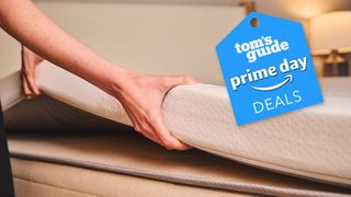 A woman lifts the 3&quot; Latex Topper onto a bed with a Prime Day Deals badge in the corner 