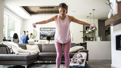 Woman exercising with dumbbells in domestic setting