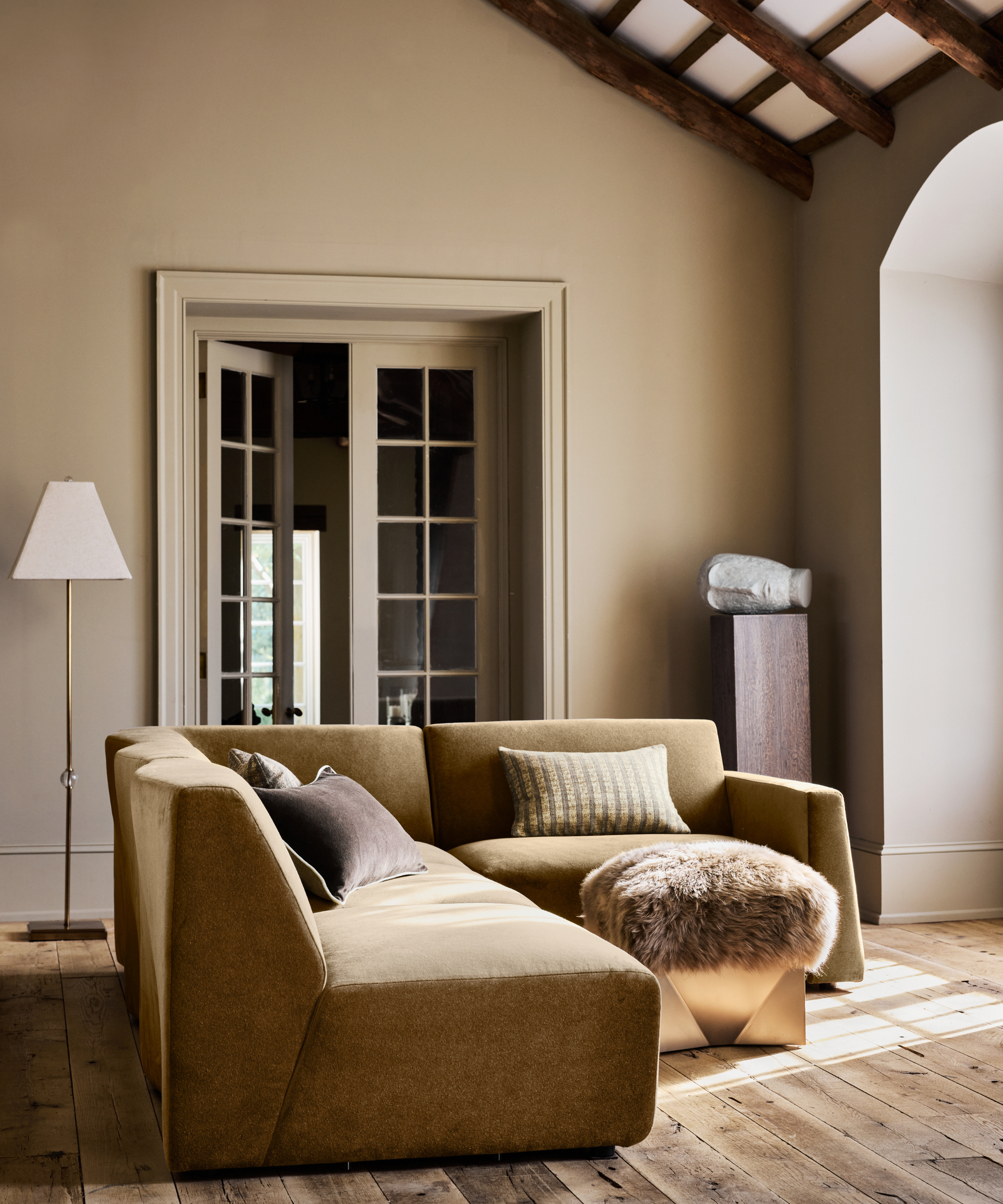 a sitting area featuring a large couch, an ottoman, and a floor lamp