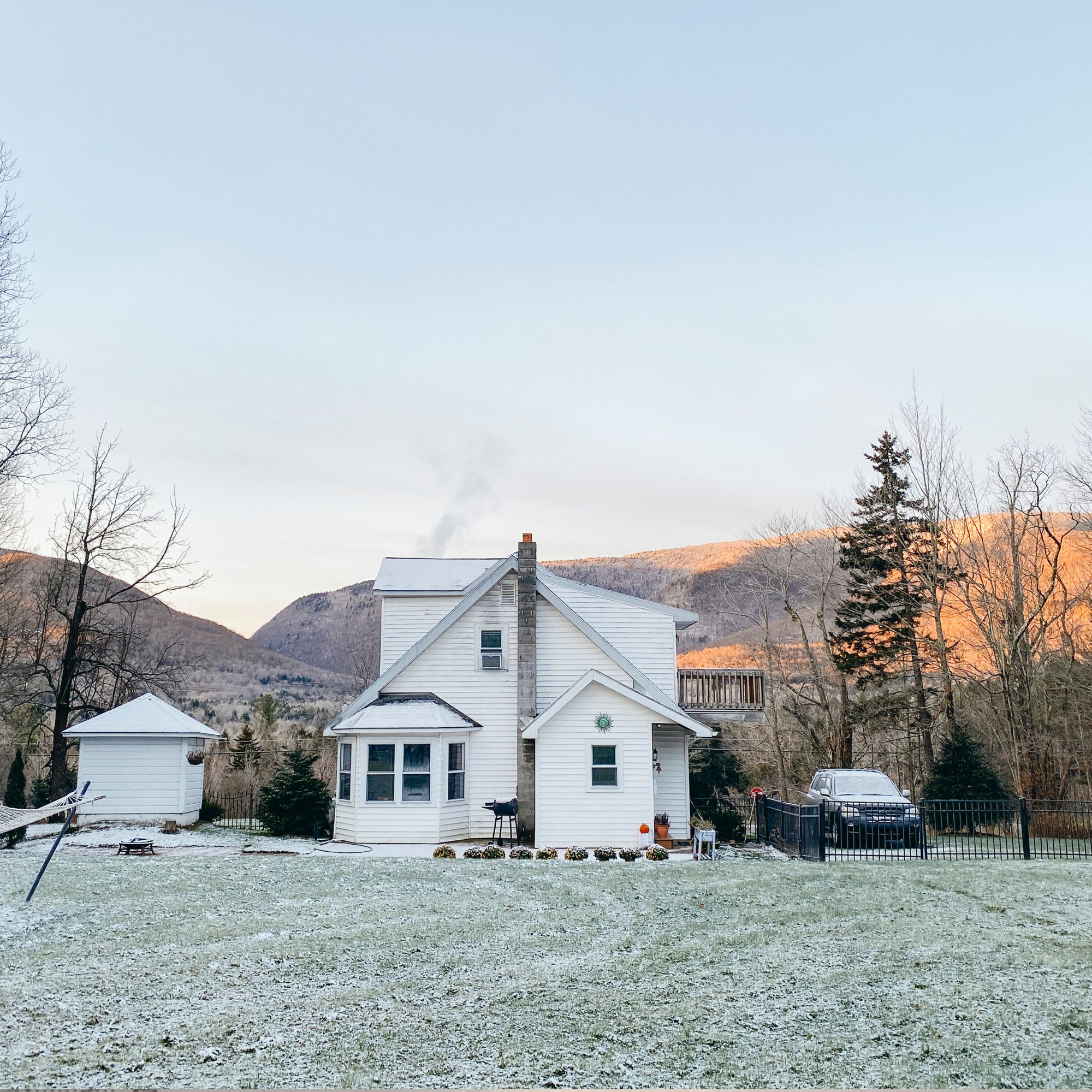 Backyard view of frosted lawn and home with mountain views in winter