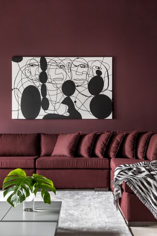 A living room color drenched in burgundy with a black artwork on walls