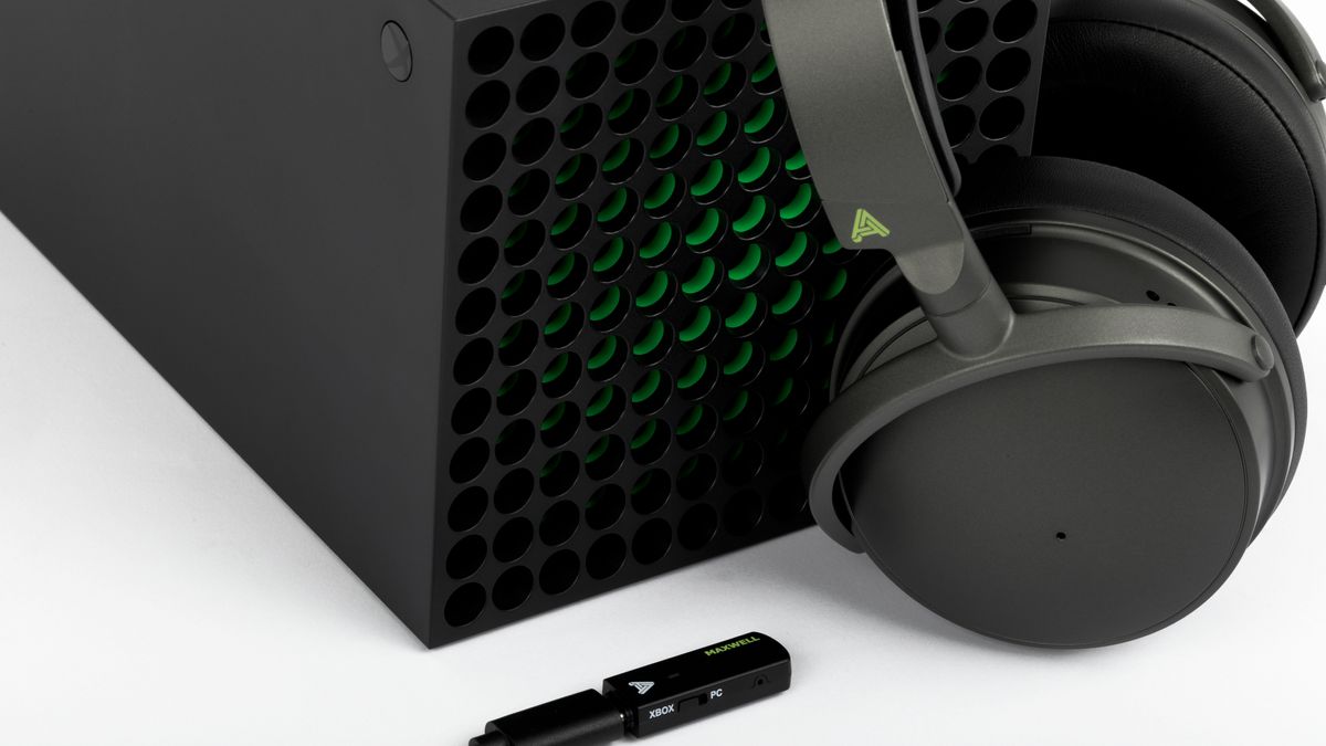 Audeze Maxwell wireless gaming headset for Xbox &amp; PC leaned against Xbox Series X with the wireless USB dongle plugged in.