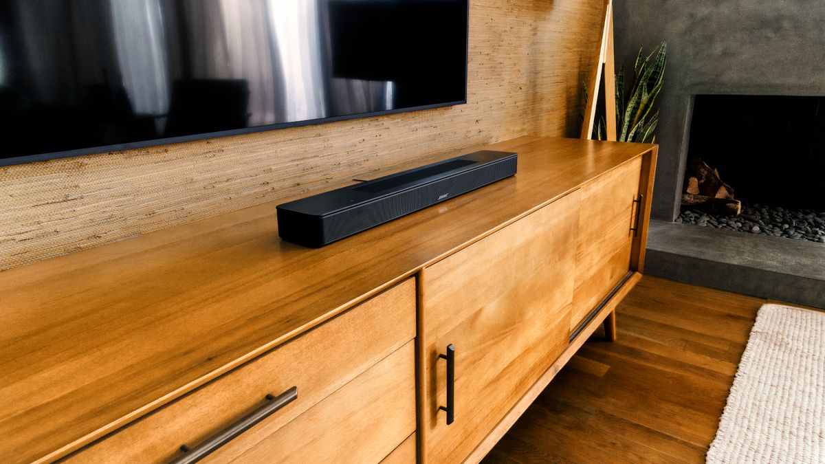 Bose Smart Soundbar on a wooden media unit underneath a TV