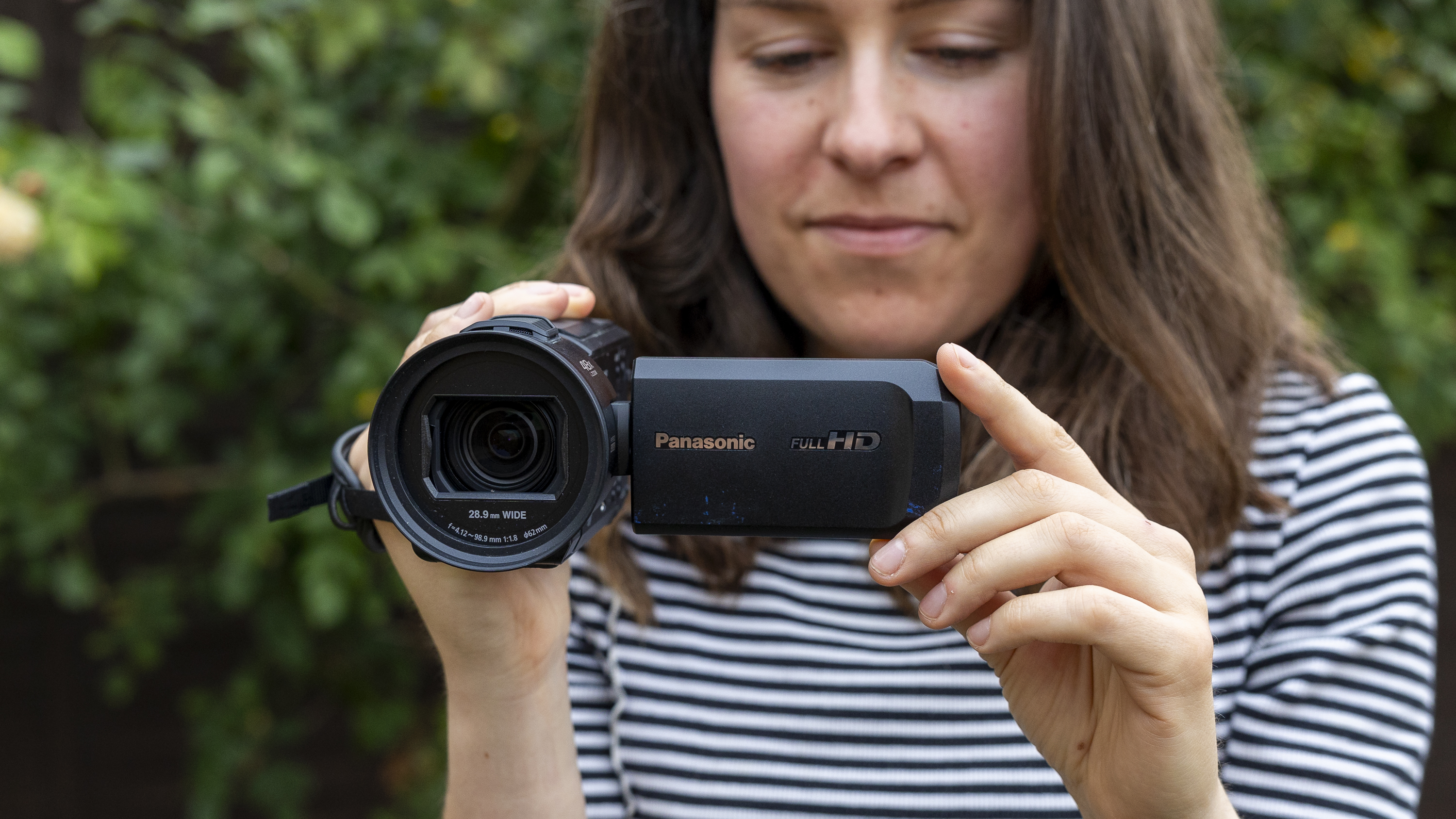 A female holding the Panasonic HC-V900 camcorder in a garden