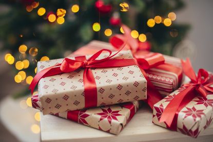 Several gift-wrapped presents with red bows underneath a Christmas tree.