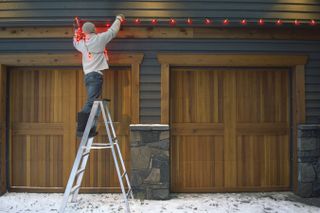 Man putting up red Christmas lights