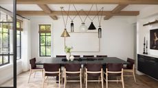black dining table in white walled room with beams and wood floor