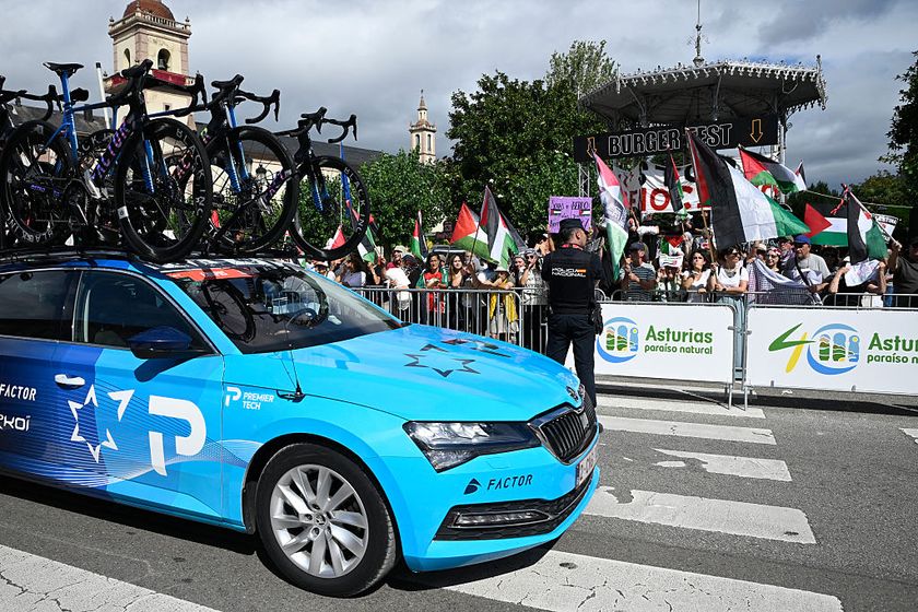 Pro-Palestinian protesters wave flags as Team Israel Premier Tech&#039;s team car drives past in Vegadeo at the start of the 15th stage of the Vuelta a Espana cycling tour, a 167 km race between A Veiga/Vegadeo and Monforte de Lemos, on September 7, 2025. (Photo by Miguel RIOPA / AFP)