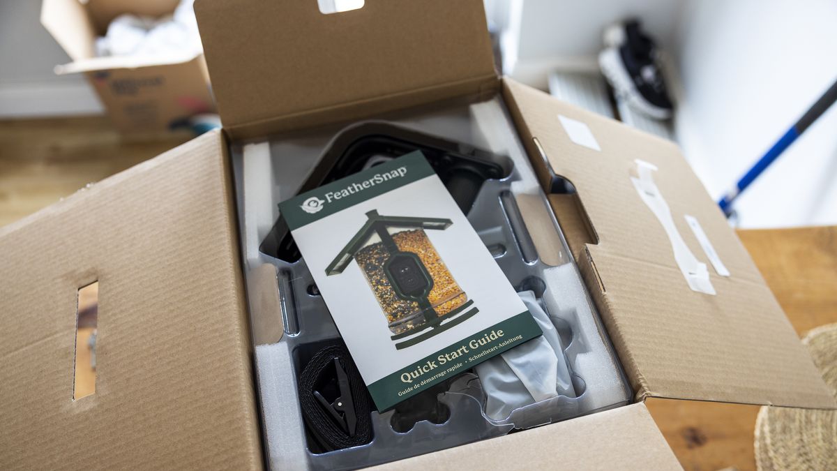 The FeatherSnap Scout bird feeder being unboxed on a wooden dining table