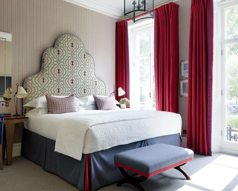 A curtain idea for French and patio doors with red drapes with blue trim and statement upholstered headboard