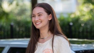 Belly smiles while standing in front of a car