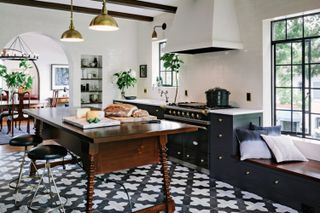 Spanish style farmhouse kitchen with vintage tiled floors and dark kitchen table with bobbin legs