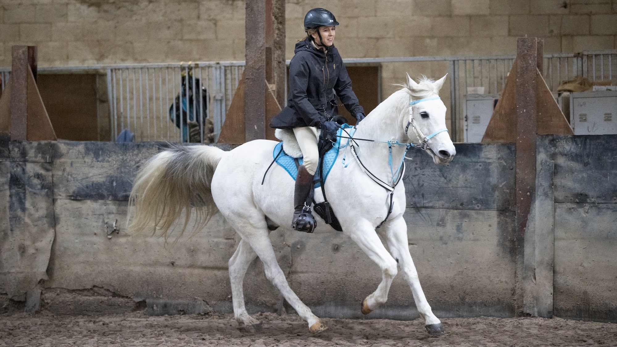 Emma Martin cantering grey Arab horse in indoor school