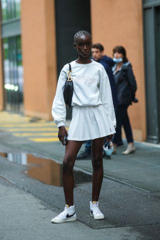 woman wearing crewneck, tennis skirt, and sneakers