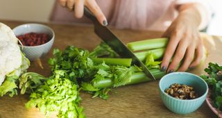 Woman's hands chopping celery with large knife