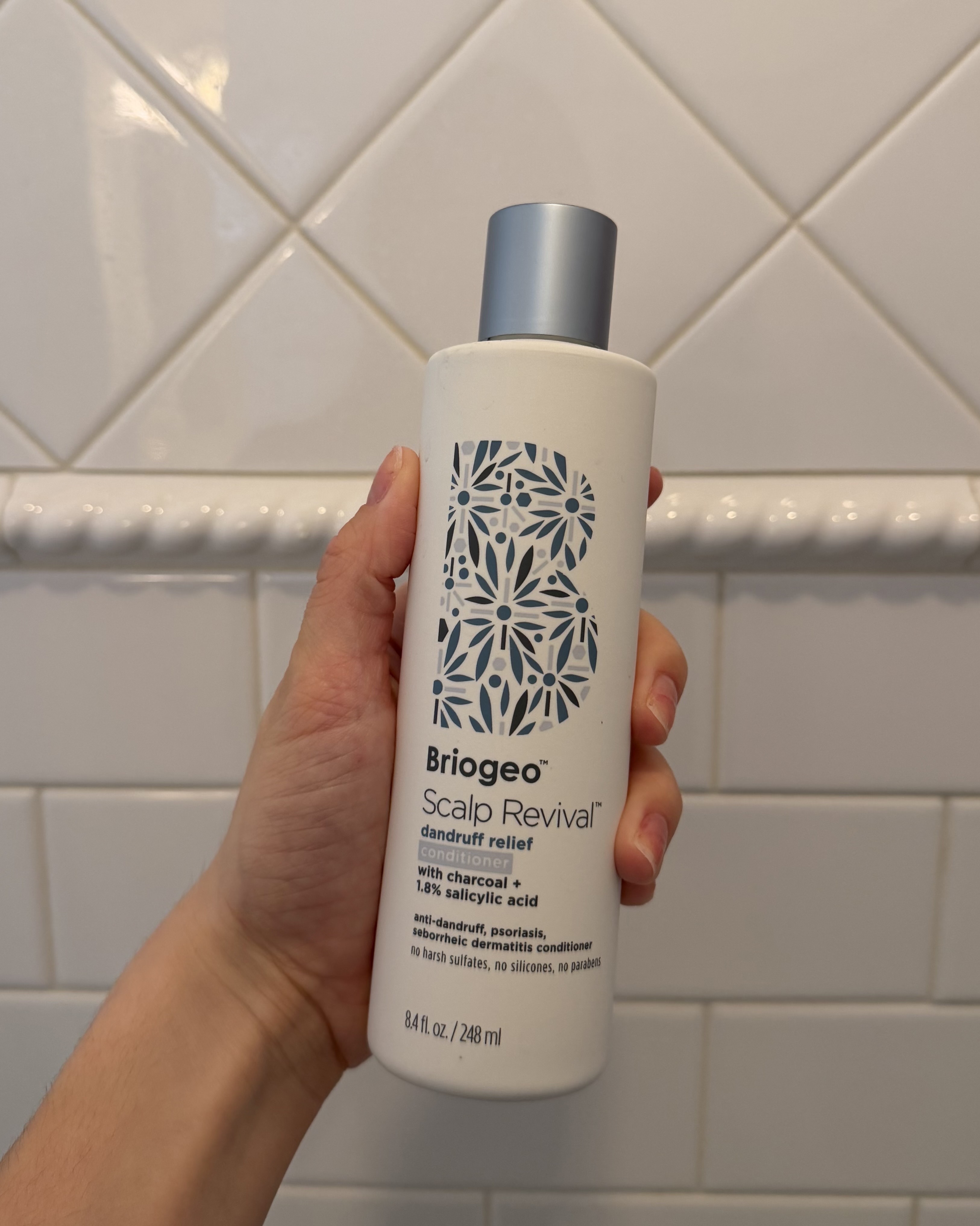 Brascia holding the Briogeo Scalp Revival Dandruff Relief Conditioner.