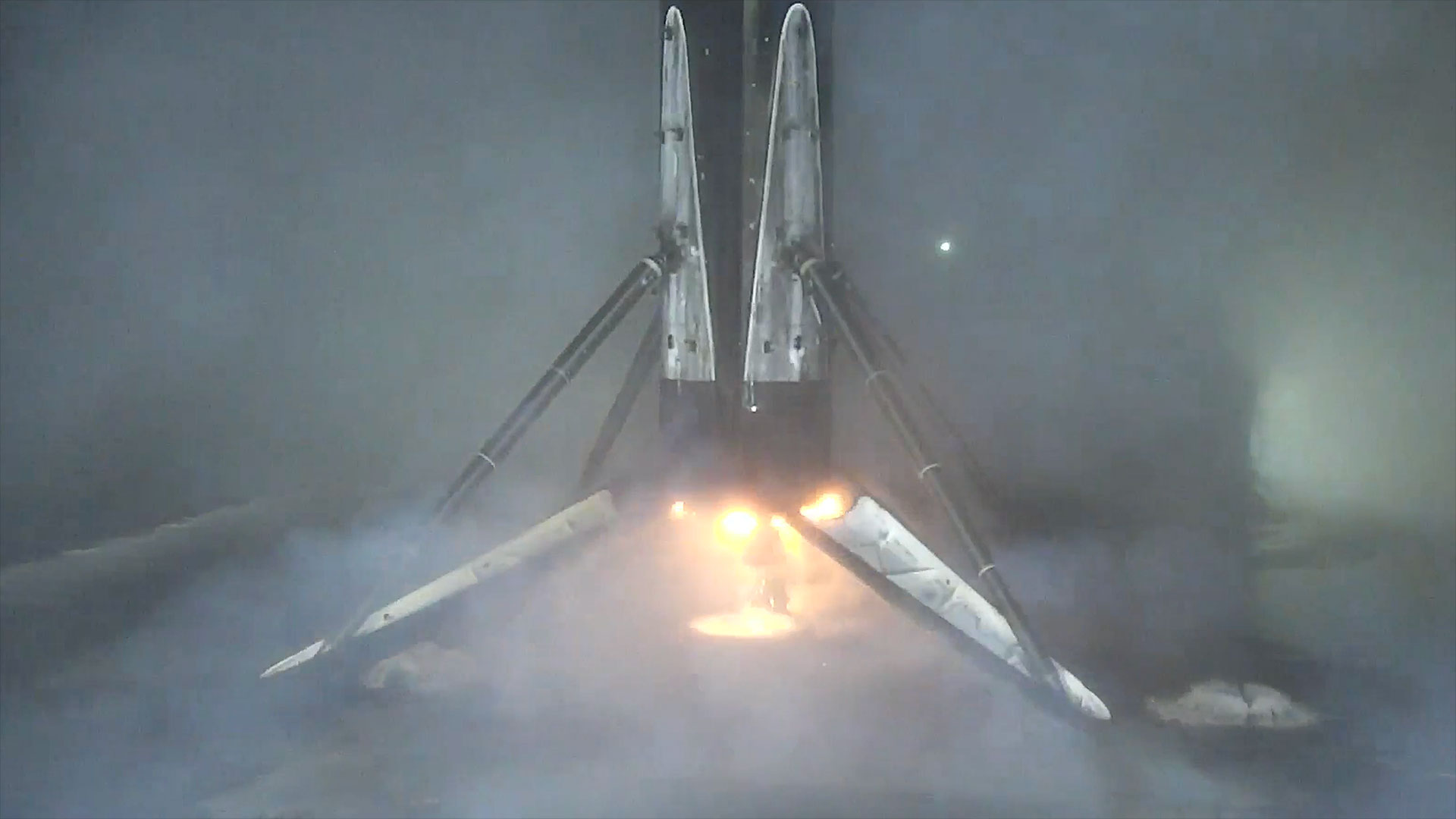 a rocket's first stage fires one of its engines to land on an ocean-based droneship, its four landing legs deployed