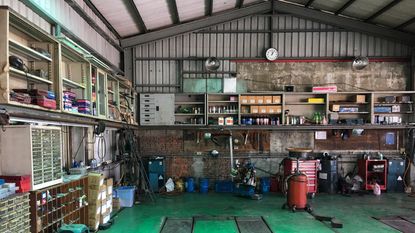 A garage with lots of tools across the shelves and a green floor