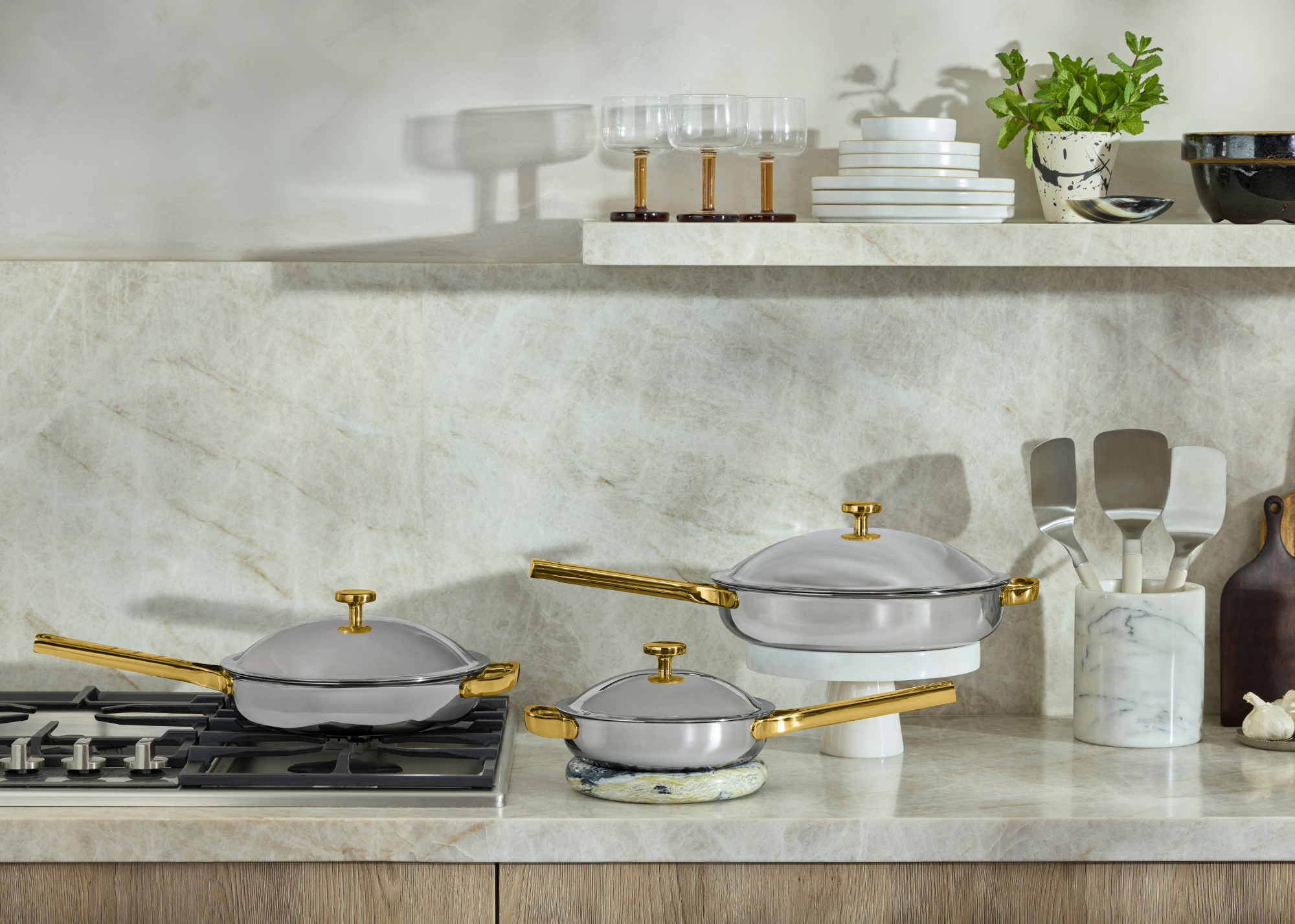 A stone kitchen counter with silver and copper lidded cooking pans