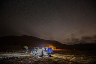 A Perseid meteor streaks across the sky above a group of campers at the Negev Desert near the city of Mitzpe Ramon, Israel, on Aug. 11, 2020.