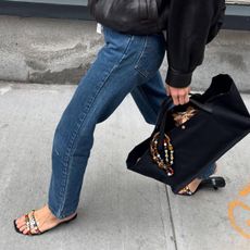 Courtney Grow wearing jeans with black beaded sandals.