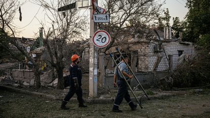 Workers walk by destroyed houses in southern Ukraine following a missile strike in Mykolaiv on 29 August