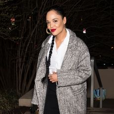 Tessa Thompson wearing a plaid coat, white shirt, and black pants