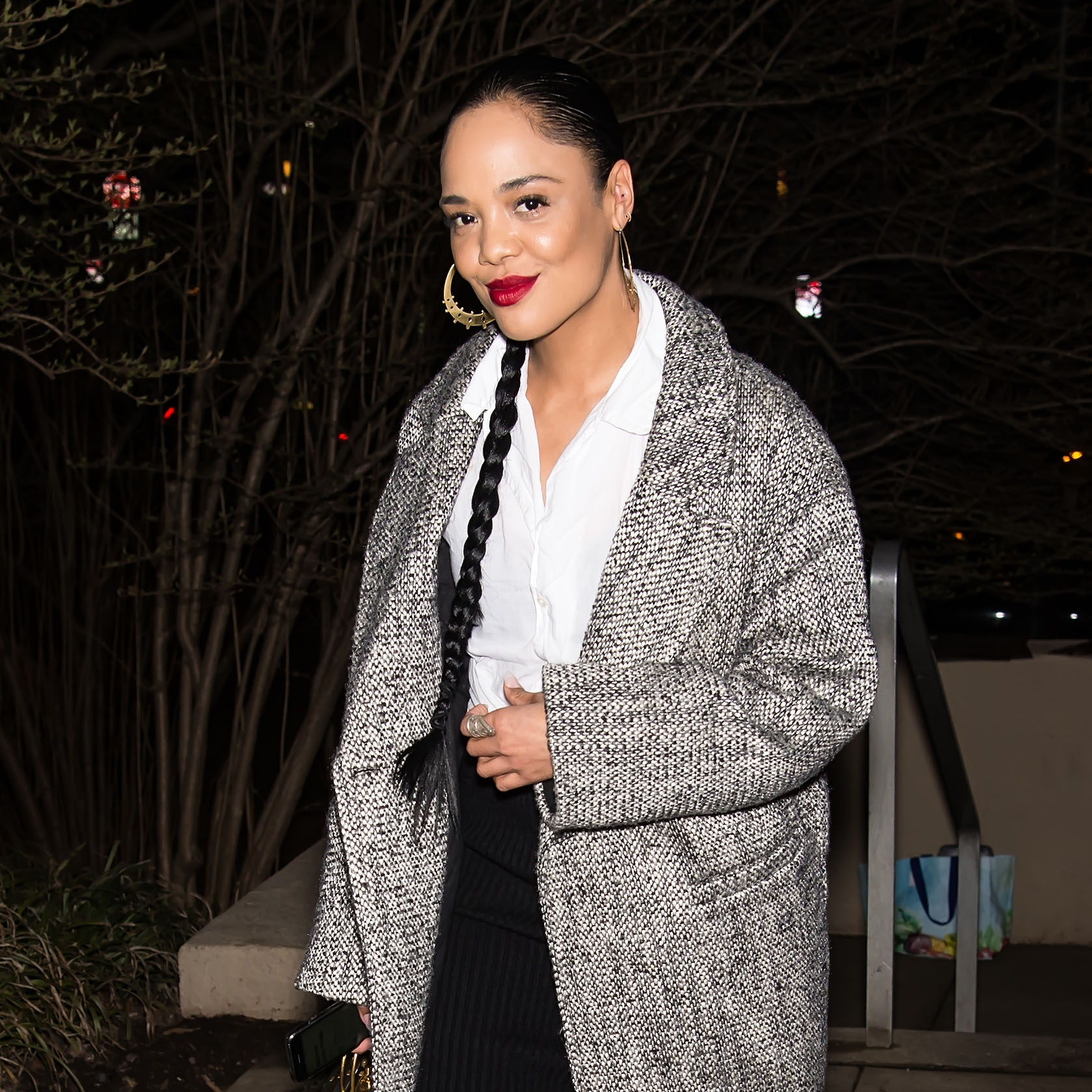 Tessa Thompson wearing a plaid coat, white shirt, and black pants