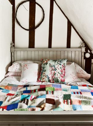 cottage bedroom with colorful patchwork quilt and beams