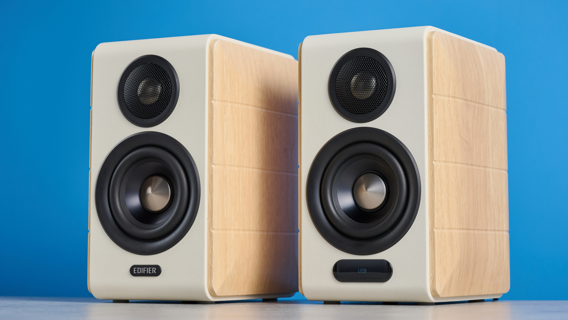 the edifier s880db mkii speakers in white and wood colorway showing the connectivity options, remote control, against a blue background