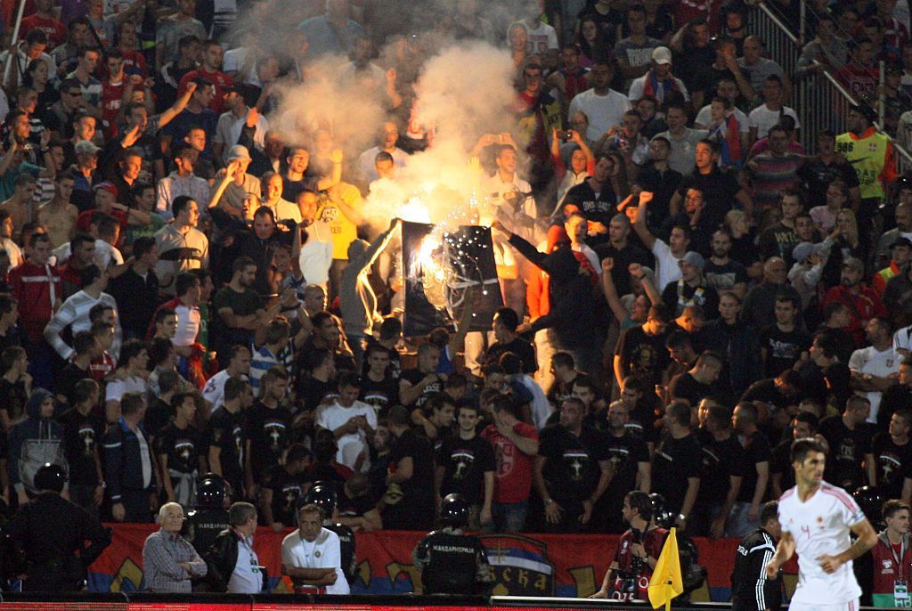 Serbian fans burn a NATO flag on October 14, 2014 during a Euro 2016 group I qualifying football match between Serbia and Albania in Belgrade. The match was abandoned after a drone carrying a pro-Albanian message was flown over the stadium, sparking violent scenes on and off the pitch. The match between the Balkan rivals was scoreless when it was stopped in the 41st minute after the drone trailing a &quot;Greater Albania&quot; flag flew over the Partizan Stadium in Belgrade and was brought down by a Serbia player. The incident triggered clashes between the two sets of players and a handful of the 20,000 Serbian spectators ran on to the pitch and tried to assault the Albanian team. 