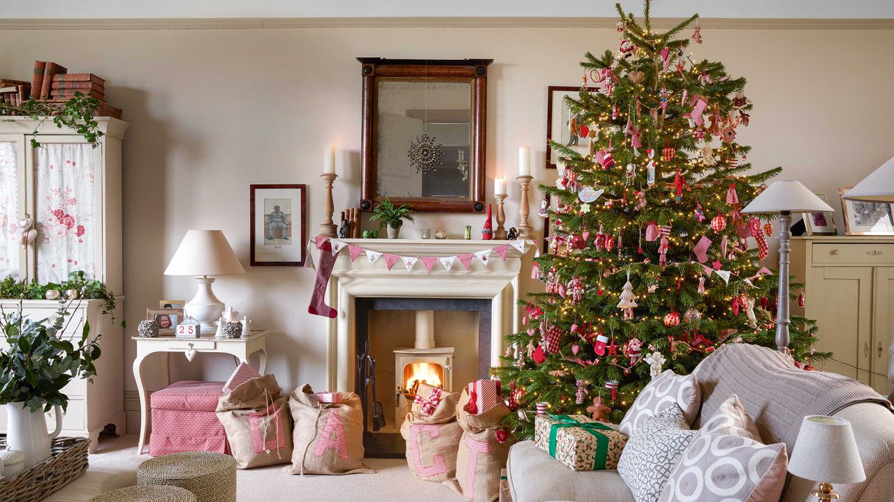 living room decorated for christmas with red and white themed tree and decorated mantelpiece