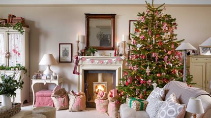 living room decorated for christmas with tree, stockings and santa sacks and fireplace with log burner
