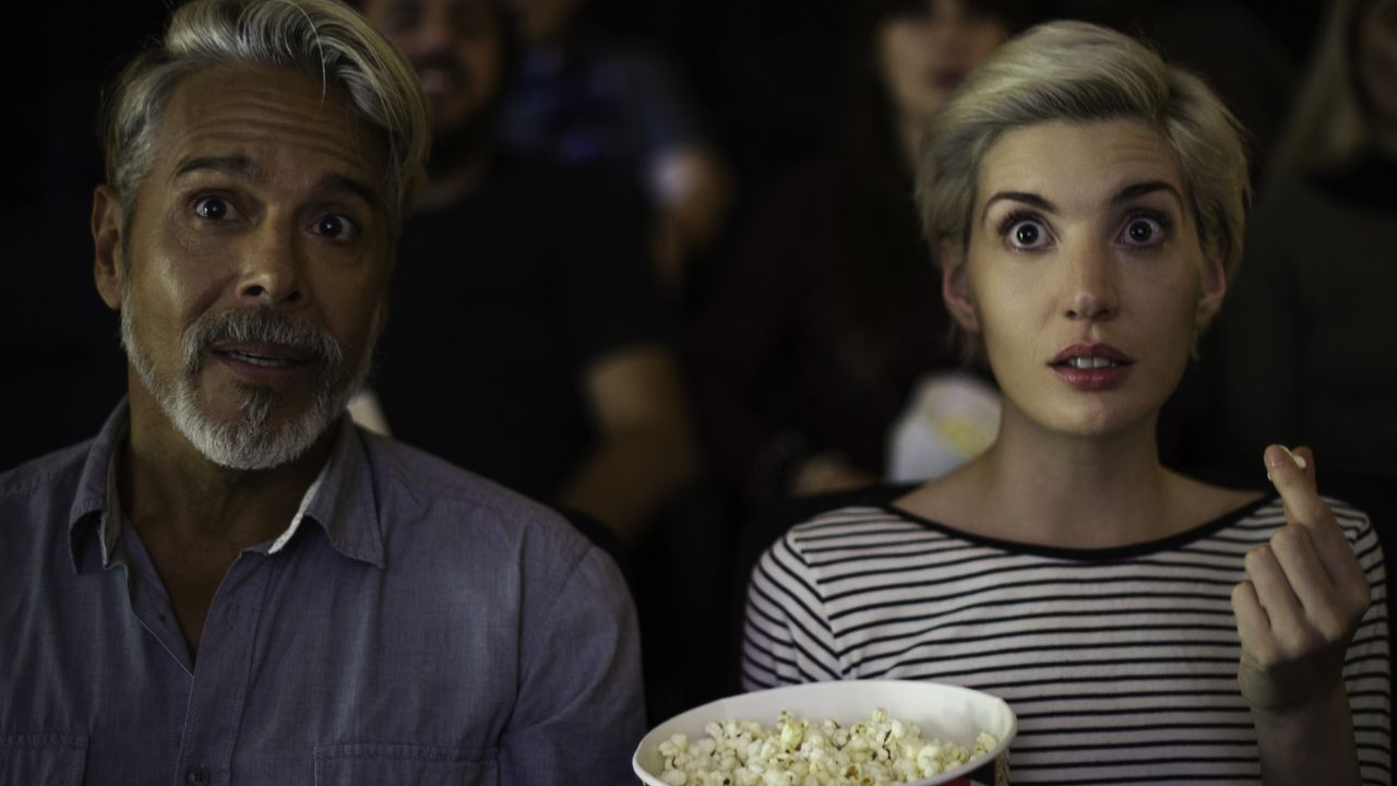 Man and a woman watching a scary movie at a theater