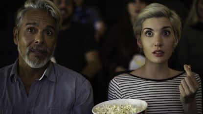 Man and a woman watching a scary movie at a theater