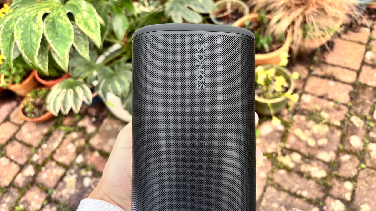 Sonos Play wireless speaker in black held in front of some flowers
