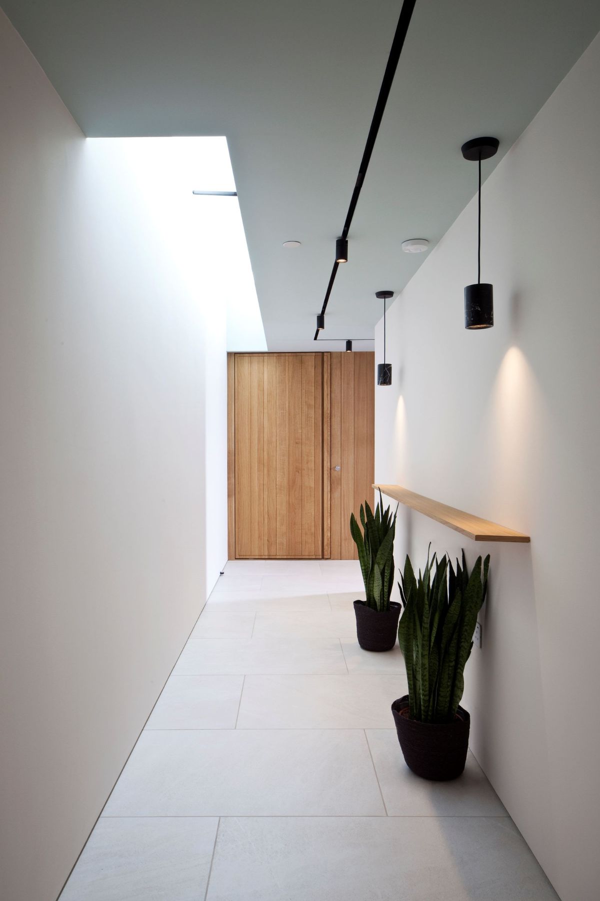 The hallway inside the triangle shaped home with daylight seeping in through the ceiling window
