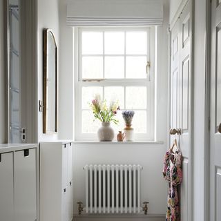 White hallway with a white radiator and flowers on the windowsill