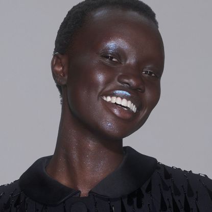 a black model with short, black hair wears blue glitter makeup