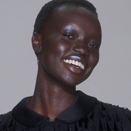 a black model with short, black hair wears blue glitter makeup