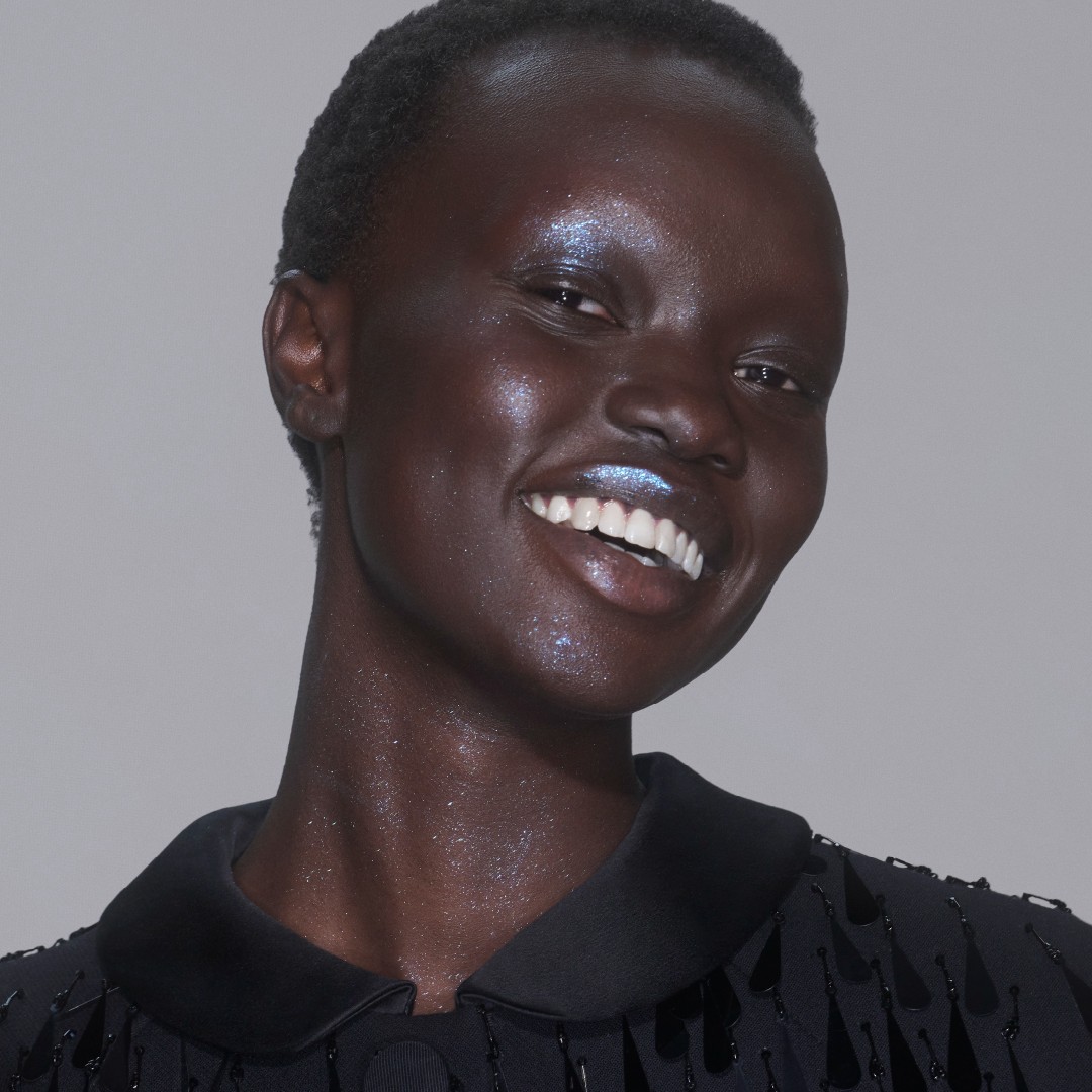 a black model with short, black hair wears blue glitter makeup
