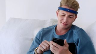 A man using his phone while wearing a blue Frenz Brainband