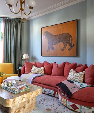 A maximalist living room with artwork and a red, curved couch
