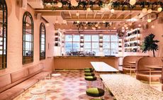 Pink colour bar, tables topped with terrazzo, pink and cream floor tiles that are laid in an asymmetrical pattern, and pendant globes, which hang from the ceiling in a representation of peaches on a tree.