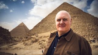 Dara Ó Briain in front of two towering pyramids in Egypt for docuseries The Mysteries of the Pyramids