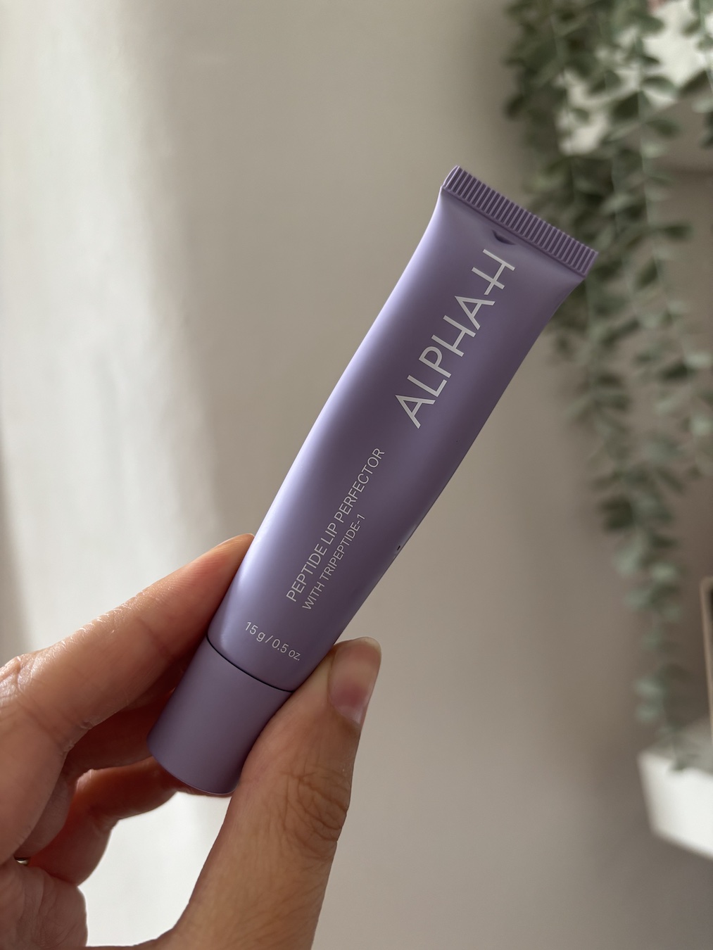 Mica Ricketts holding Alpha-H Peptide Lip Perfector
