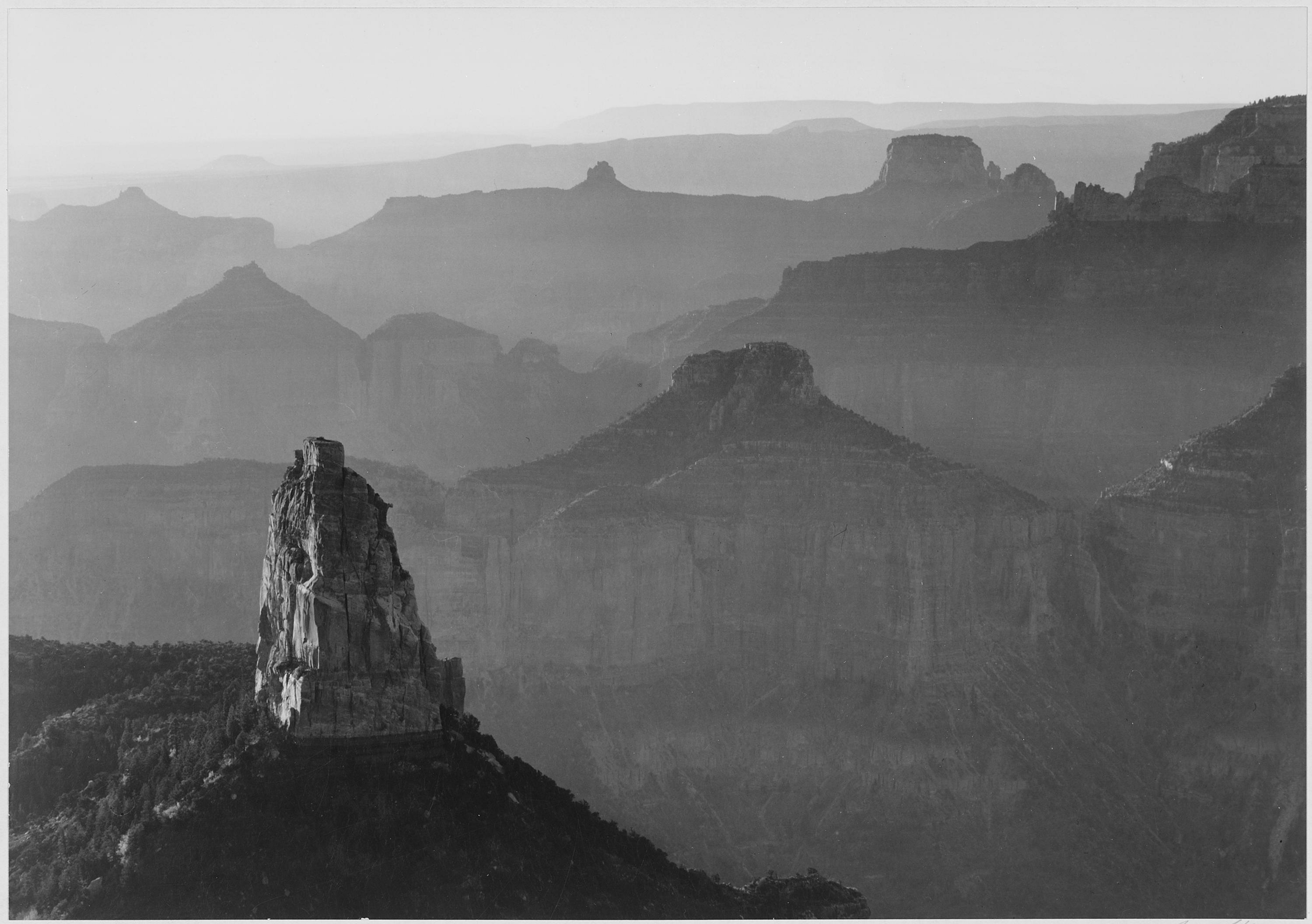 Black and white photograph, view with rock formation in foreground, captioned "Grand Canyon National Park", by Ansel Adams, from Photographs of National Parks and Monuments