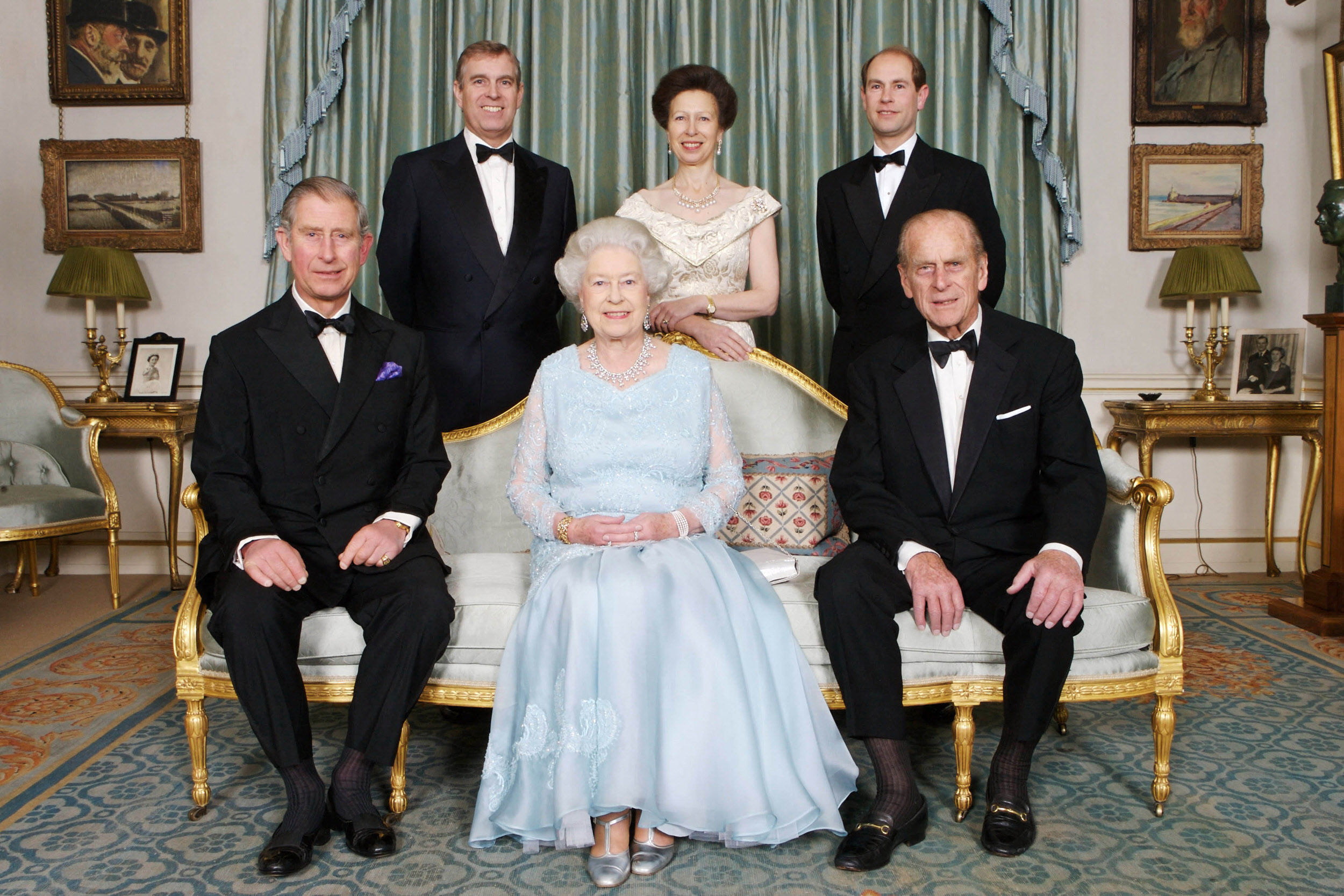 Queen Elizabeth sitting on a sofa between King Charles and Prince Philip with Prince Edward, Princess Anne and ex-Prince Andrew standing behind them