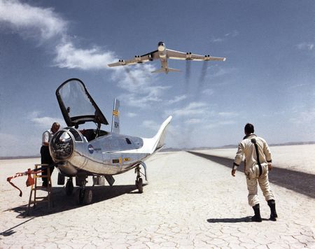 NASA research pilot Bill Dana watches NASA's NB-52B overhead after a flight in the HL-10 lifting body. The HL-10 was one of five lifting body designs flown at NASA's Dryden Flight Research Center in California, from 1966-1975 to study maneuvering and landing a low lift-over-drag vehicle designed for reentry from space.