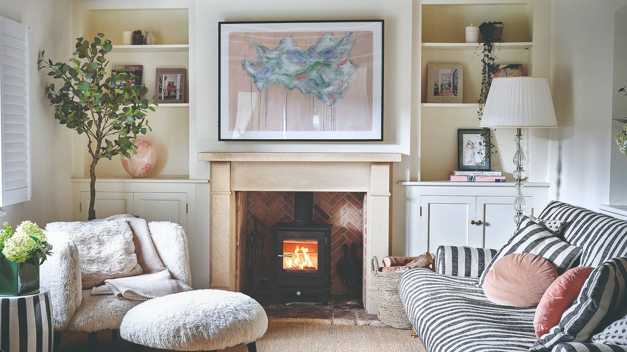 A living room with a striped sofa and a large artwork hung above the fireplace